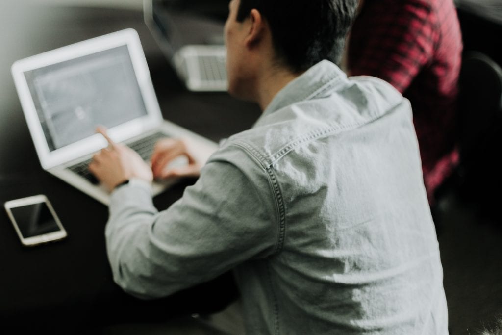 An image of a man sitting in front of a computer.